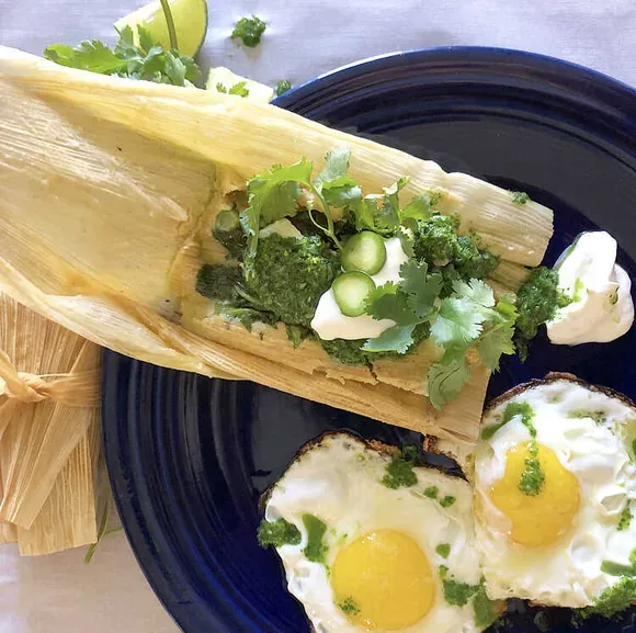 Unwrapped tamales, slow-cooked and finished with eggs, herbs, and a bright green sauce